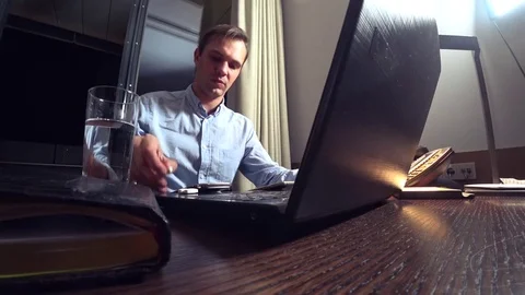 Man working on a laptop at a table at night in a hotel room. 4k. Stock Footage 83169383