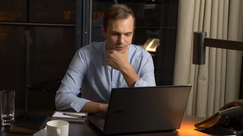 Man working on a laptop at a table at night in a hotel room. Stock Footage 87916952
