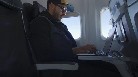 Man working on laptop while sitting on airplane Stock Footage 122184523