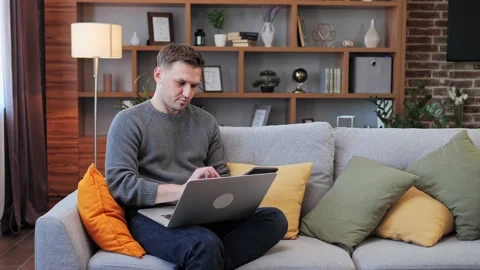 Man Working on Laptop while Sitting on Couch at home. Business, manage budget. Stock Footage 172394401
