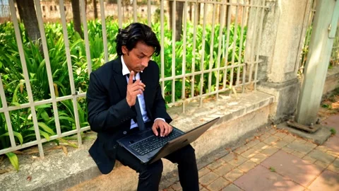 Man working on laptop while sitting outdoors Stock Footage 277035553