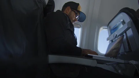 Man working on laptop while traveling on airplane Stock Footage 122184250