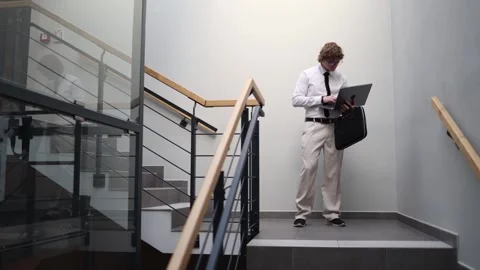 Man working on laptop while walking downstairs multitasking Stock Footage 333973590