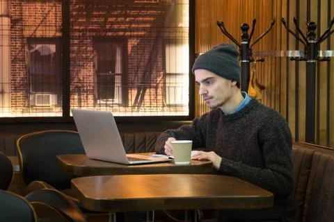Man working late hours at cafe with laptop and note pad. Young male in casual Stock Photos