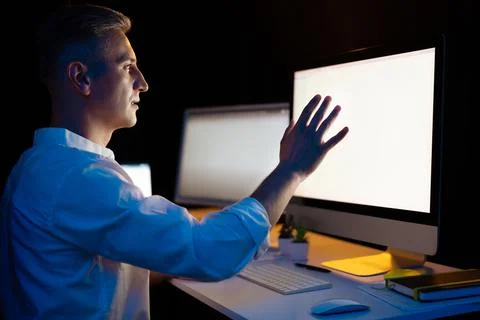 Man Working Late Night On Computer Touching Screen Foto stock