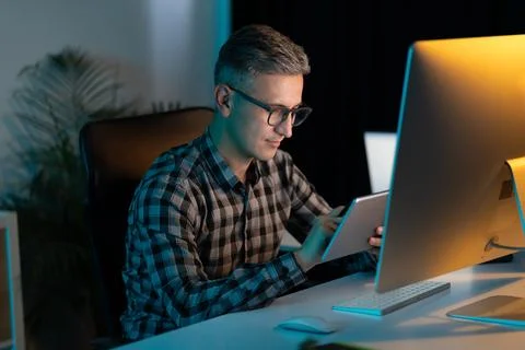 Man Working Late at Night on Digital Tablet in Office Stock Photos