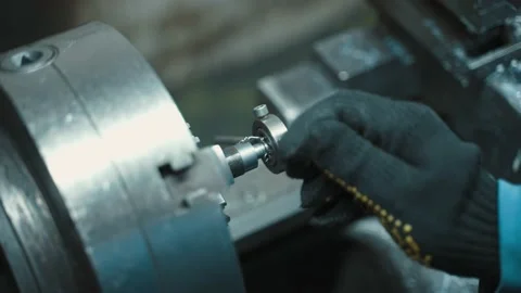 A man working on a lathe in a workshop cutting threads into parts Stock Footage 225462598