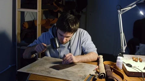 Man working on leather, making holes using hummer Stock Footage 71390727