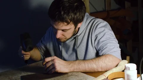 Man working on leather, making holes using hummer Stock Footage 71391074