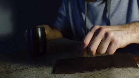 Man working on leather, making holes using hummer Stock Footage 71391085