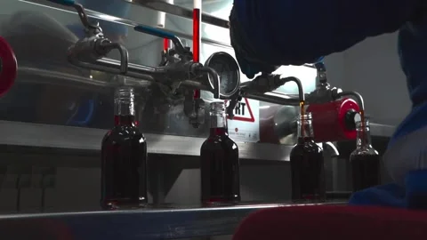A man working on a machine to fill bottles with liquid in a factory. Stock Footage 274356867