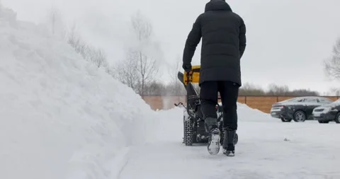 Man working with manual snow blower. Snowy winter. Man removes snow snowdrifts Stock Footage 169758600