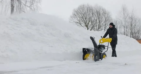 Man working with manual snow blower. Snowy winter. Man removes snow snowdrifts Stock Footage 169882989