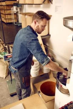 Man working with a modern coffee bean roasting machine Stock Photos
