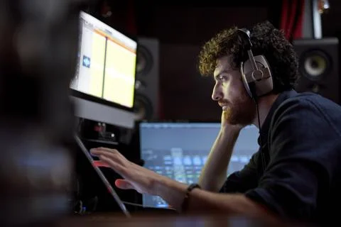 Man working in music studio using computer wearing head phones Stock Photos