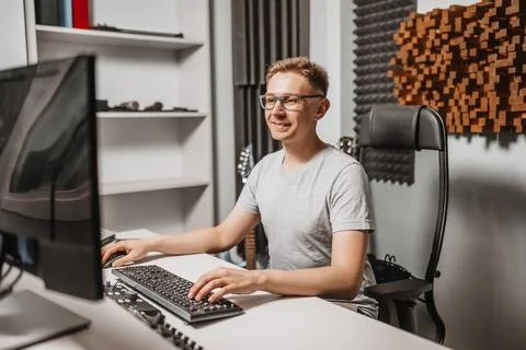 Man working in music studio using computer wearing glasses. Sound engineer wo Stock Photos