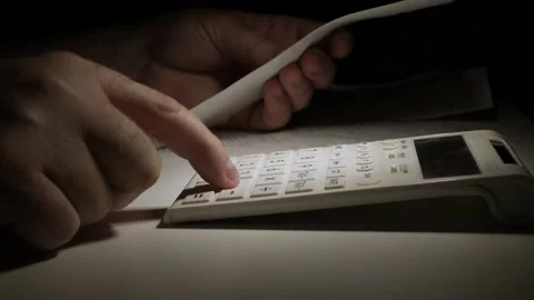 Man Working at Night, with Financial Documents  Using Adding Machine. Stock Footage 154793333