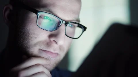 Man working at night lying down on sofa in the living room with tablet. Видео 58821048