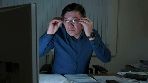A man working at night in the office at the computer puts on glasses Stock Footage 150453775