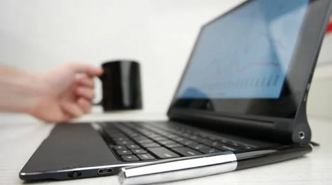 Man working on a notebook using touchscreen, with financial charts displayed. Bu Stock Footage 60392266