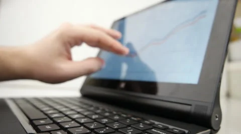 Man working on a notebook using touchscreen, with financial charts displayed.  Stock Footage 60392347