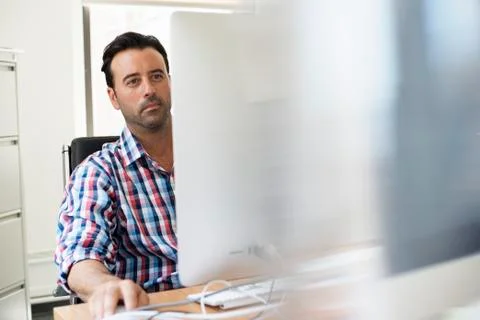 A man working in an office at a desk using a computer. Foto stock