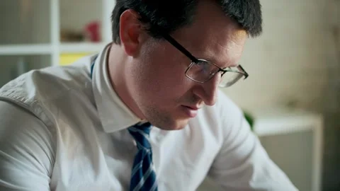 Man working with office documents removes glasses and rests his eyes. Video stock 325729419