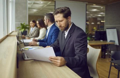 Man working in office, doing business research, reading paper report, and using Foto stock