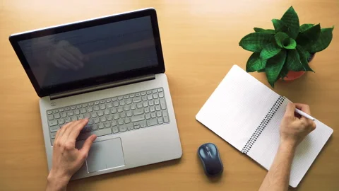 Man working at office with laptop and notepad, hands top view Stock Footage 87872995