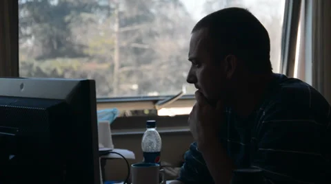 Man working in the office next to the window, watching monitor Stock Footage 39789446