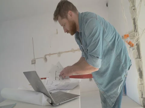 Man working in the office on the project about new flat, steadycam shot Stock-Footage 76492567