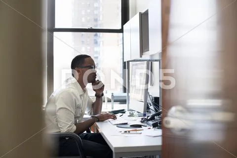 A man working in an office seated at a desk. looking at a computer screen. Stock-Fotos