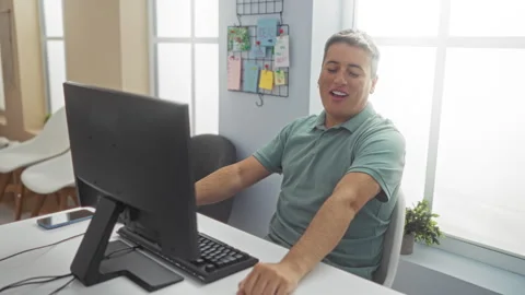 Man working in an office, smiling at his computer with a modern setup in a .. Stock Footage 284284379