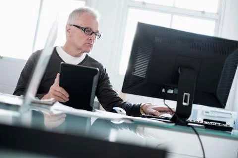 Man working in office using computer and tablet Foto stock