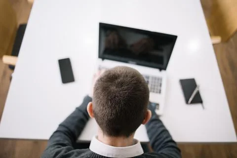 Man working at office using laptop while sitting on desk Foto stock