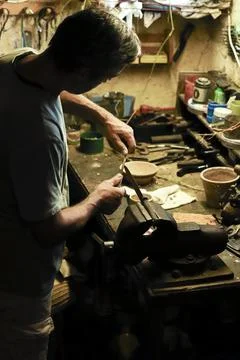 Man working in an old retro workshop with dim light. Atmospheric. Stock Photos