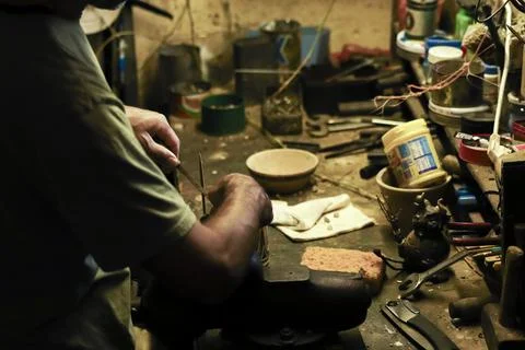 Man working in an old retro workshop with dim light. Atmospheric. Stock Photos