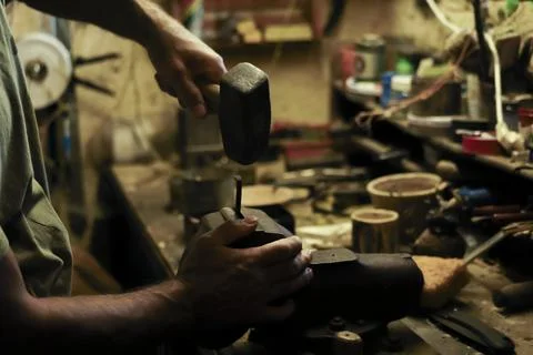 Man working in an old retro workshop with dim light. Atmospheric. Stock Photos