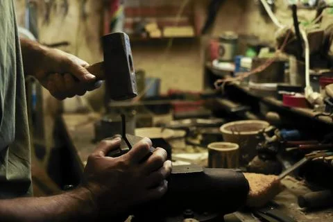 Man working in an old retro workshop with dim light. Atmospheric. Stock Photos