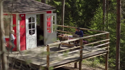 Man working online on laptop and talking with family on country house porch Stock Footage 195352499