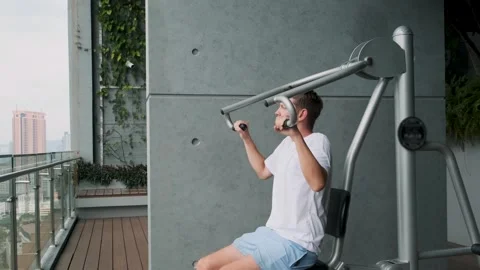 Man working out on chest press fitness machine in outdoor gym on modern balcony Stock Footage 280983720