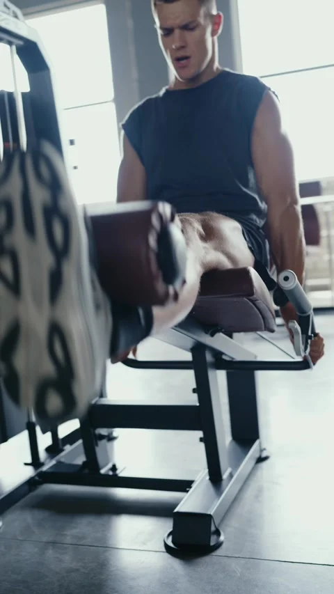 Man Working Out at Gym Using Leg Extension Machine for Strength Training Stock Footage 315282380