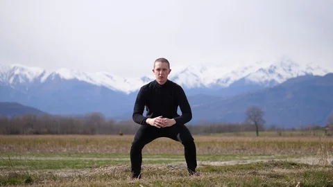Man Working Out in the Wild, Doing Jump Squats Stock Footage 125442243