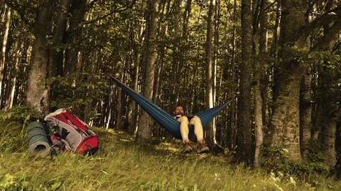 Man working outdoors with laptop in hammock Stock Footage 133327902