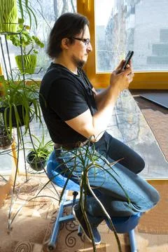 A man working on a phone while sitting on a Orthopedic ergonomic kneeling cha Stock Photos