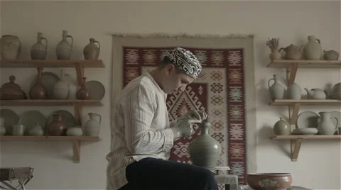 Man working on pottery wheel, shaping a clay pot Видео 68010047