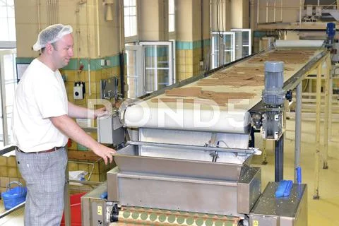 Man Working At Production Line With Dough In A Baking Factory