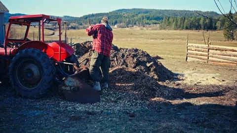 Man Working with Red Utility Tractor Beside Dark Earth Pile - Norway 스톡 동영상 344954856