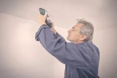 Man working on refresh of ceiling before new painting of apartment Stock Photos