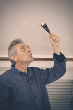 Man working on refresh of walls and ceiling before new painting of apartment Stock Photos